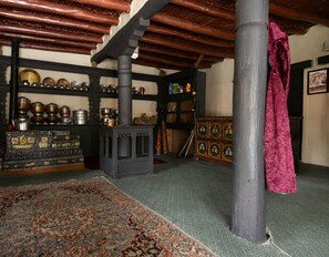 Una stanza con travi in legno dal sapore tradizionale, una tappezzeria decorata e mensole piene di oggetti assortiti, tra cui contenitori metallici e scatole decorative.