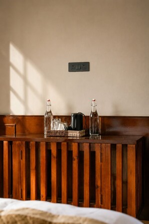 A wooden reception desk with two bottles, a coffee pot, and a basket.