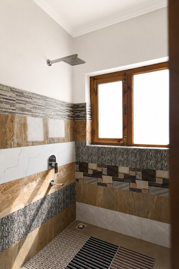 Une salle de bain avec une douche, une fenêtre et un mur carrelé présentant un mélange de motifs et de textures.