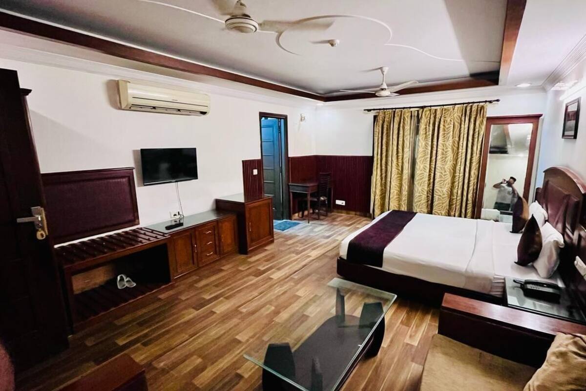 A hotel room with a bed, a TV, a desk, and a chair.