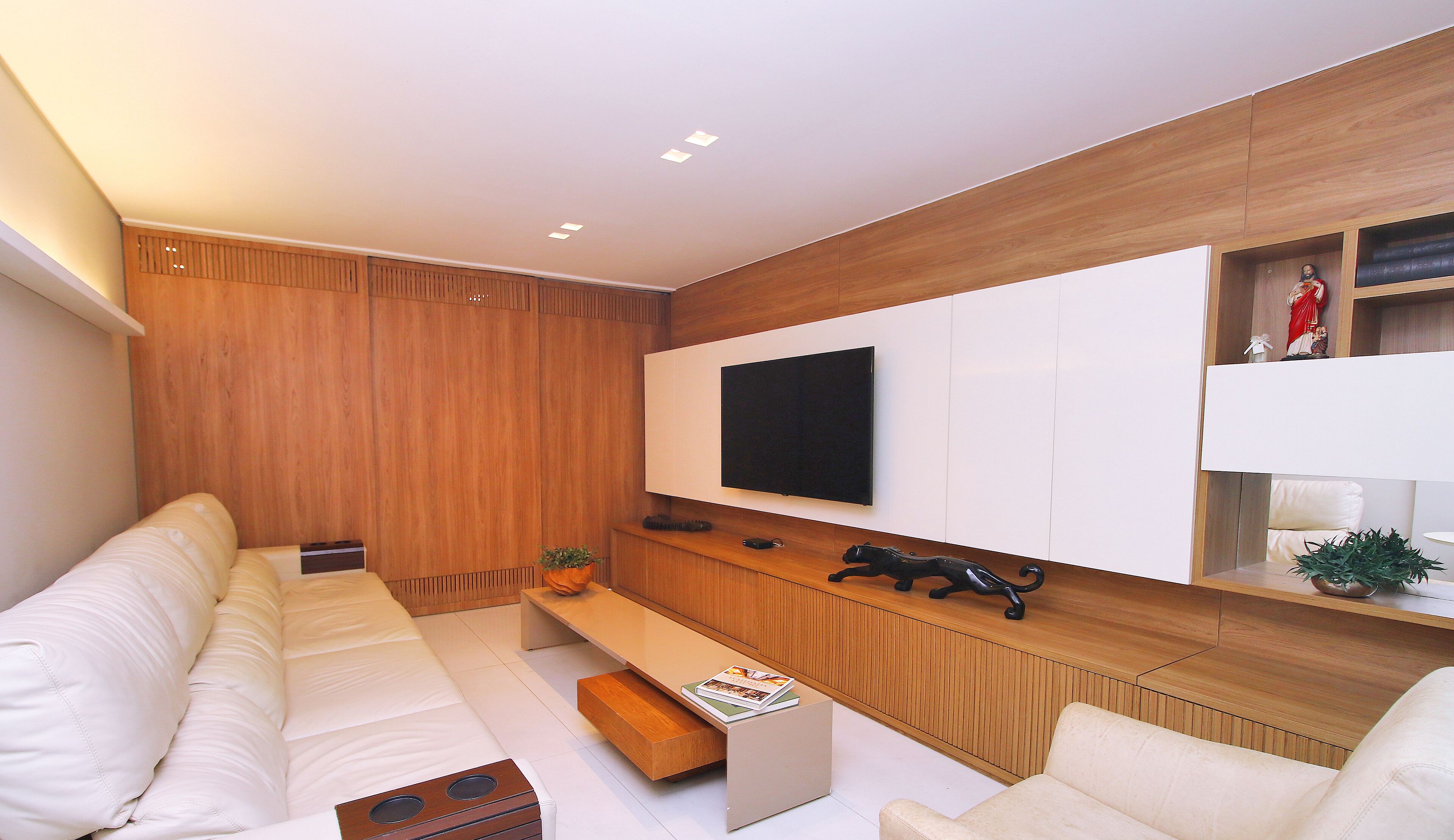 A modern living room with a white sofa, a wooden coffee table, and a mounted TV.