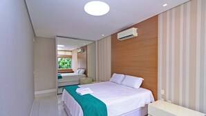A modern hotel room with a large bed, a bedside table, a mirror, and a window with a view of greenery. - Aristides Leblon (Rio de Janeiro)