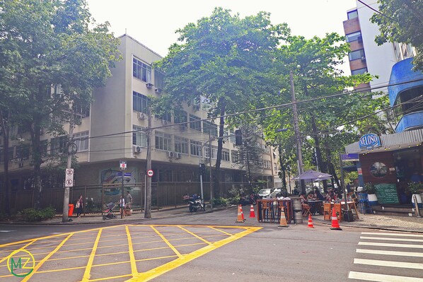A street view with a building, trees, and a restaurant. - Aristides Leblon (Rio de Janeiro)