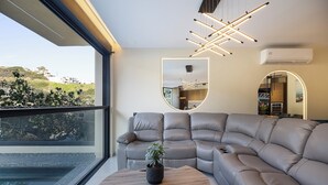A modern living room with a large sectional sofa, a round coffee table with a plant, and a view of a swimming pool through large windows. - Elmima Villa  (Mylopotamos)