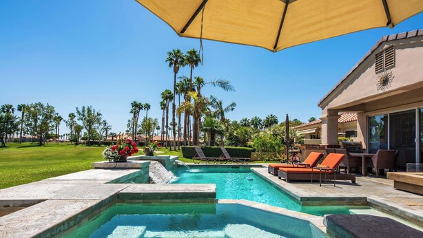 A swimming pool with a sun umbrella, lounge chairs, and palm trees. - Casa Solara | PGA West Pool, Spa & Firepit (La Quinta)