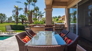 An outdoor patio with wicker furniture, a glass-top table, and a grill. - Casa Solara | PGA West Pool, Spa & Firepit (La Quinta)