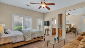 A bedroom with a bed, a glass coffee table, a sofa, and a ceiling fan. - Casa Solara | PGA West Pool, Spa & Firepit (La Quinta)