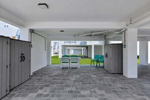 An indoor space with a tiled floor, a table with chairs, and a view of a building outside.