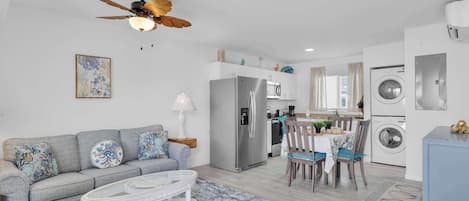 Una sala moderna con un sofá gris, una mesa de centro y un ventilador de techo.