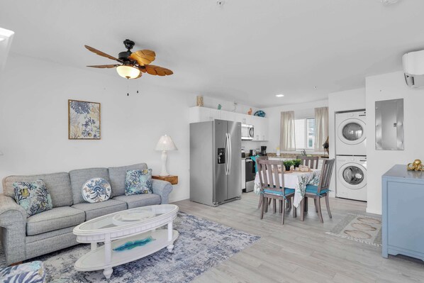 A modern living room with a grey sofa, a coffee table, and a ceiling fan.