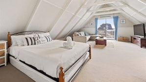 A bedroom with a sloped ceiling, a bed with white bedding, a wooden headboard, a television, and a view of the outdoors. - Canal view • Pet friendly • Private Jetty • Spacious Yard (South Yunderup)