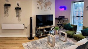 Un salon moderne doté d’un téléviseur à écran plat, d’une carte du monde, d’un néon et d’un piano.