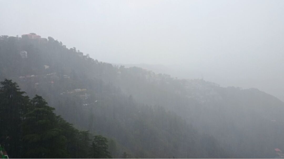 A foggy mountain landscape with buildings on the slopes.