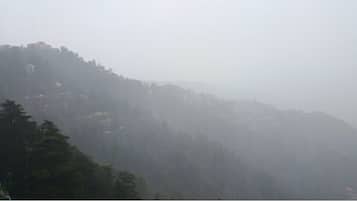 A foggy mountain landscape with buildings on the slopes.
