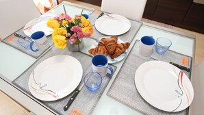 Ein Esstisch gedeckt mit Tellern, einer Blumenvase und einem Teller Croissants.
