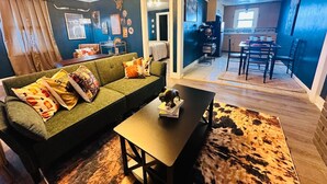 A cozy living room with a green sofa, a coffee table, and a cowhide rug.