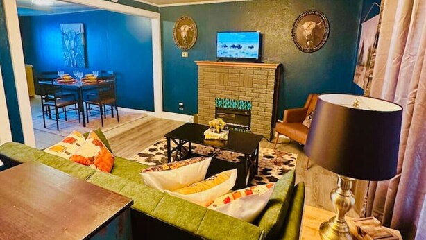 A cozy living room with a green sofa, a wooden coffee table, and a television on a brick fireplace.