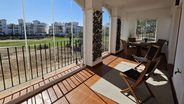 Ein Balkon mit Blick auf eine Wohngegend, einem Esstisch mit Stühlen und einem Blumentopf.