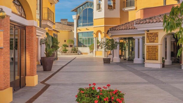 A courtyard with yellow buildings, a bar, and potted plants. - Very nice apartment at La Torre Golf Resort AO3711 (Murcia)