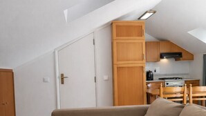 A loft-style room with a sofa, a dining table, a kitchenette, and a door. - T0 Condomínio jardim da Oura, A/c, piscinas, terra (Albufeira)