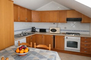Une cuisine avec des meubles de rangement en bois, un four à micro-ondes, une cuisinière et un évier.
