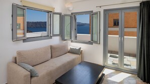Una habitación con sofá, mesa de centro y grandes ventanales con vistas al mar.