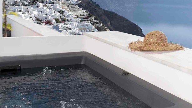 Una piscina en la azotea con vistas a un pueblo costero y montañas.