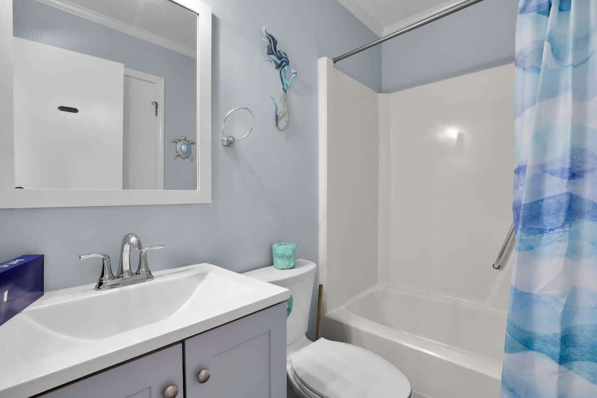 A bathroom with a white sink, a mirror, a toilet, and a shower.