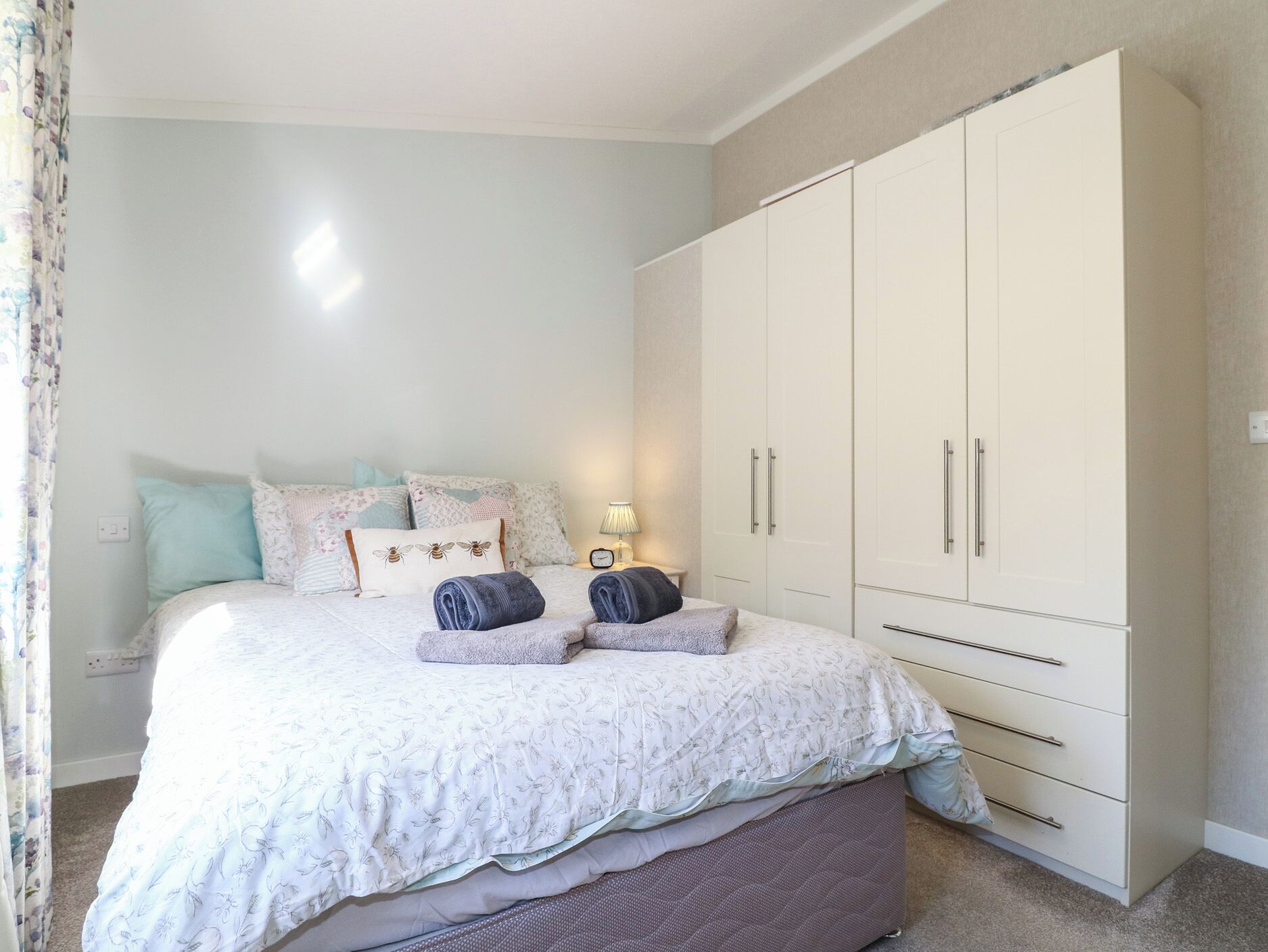 Un dormitorio con cama, almohadas, una mesita de noche, lámpara y armario.