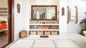 A modern bathroom with a large mirror, wooden shelves, and a white tiled floor. - Swiss 2 Villa in Dalung (Tibubeneng)