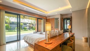 Un dormitorio moderno con una cama grande, un escritorio de madera y vistas a un jardín.