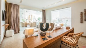 A modern living room with a wooden coffee table, wicker chairs, a TV, and a large window with blinds. - Niko 2 R New Villa Close to Finns Beach Club (Canggu)