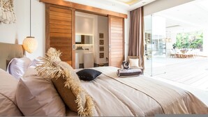 A modern bedroom with a large bed, a sliding door to a bathroom, and a view of an outdoor dining area. - Niko 2 R New Villa Close to Finns Beach Club (Canggu)