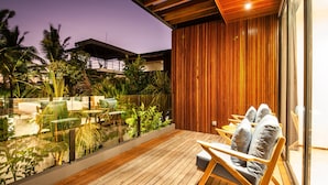 A wooden deck with a seating area, surrounded by lush greenery and a view of a building. - Noma 5 Victum in Pererenan (Pererenan)