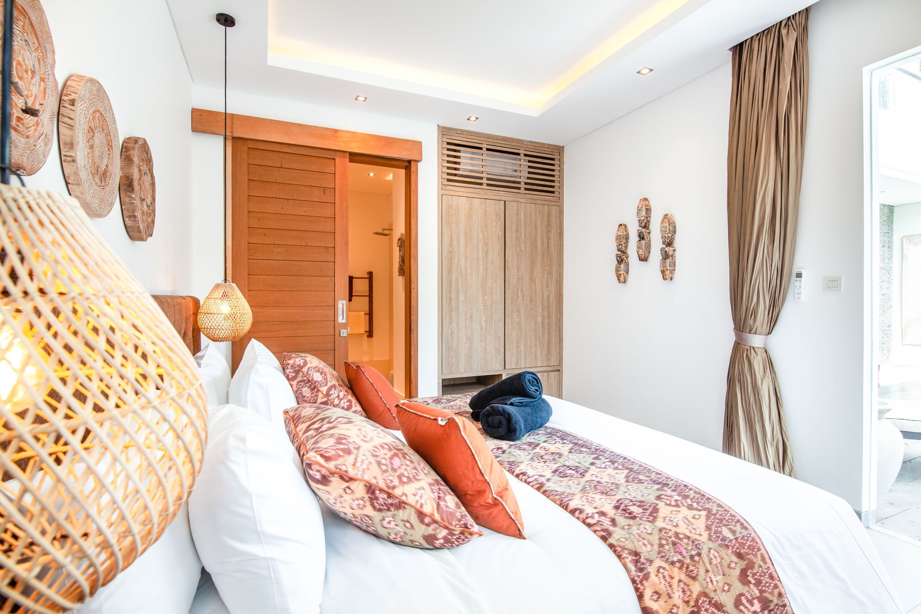 A modern bedroom with a large bed, wooden wardrobe, and a view of the outdoors.