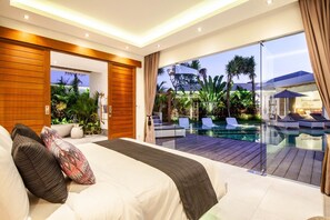 Quarto moderno com uma cama grande, vista para uma piscina e varanda com mobiliário de exterior.