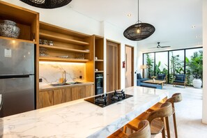 A modern kitchen with a marble countertop, wooden cabinets, and a built-in stove. - Noma 6 Dollar in Pererenan (Munggu)