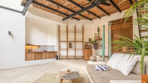 A spacious living area with a high ceiling, a built-in wooden shelf unit, a sofa with cushions, a round coffee table, and a large potted plant. - BA Villa 9 1 BR Villa 800m to Echo bea Elegant 1-br Villa With Pool 800m to Echo Beach (Pererenan)