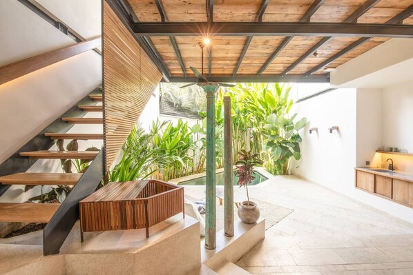 Un intérieur moderne avec un escalier, un banc en bois et une plante en pot.