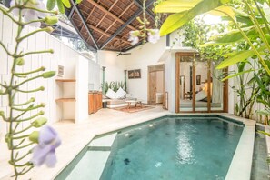 A modern indoor pool area with a clear pool, wooden deck, and seating area.