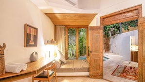 A room with a wooden desk, a cushioned bench, a large window with curtains, and a view of a pool area. - BA Villa 5 1 Bed Villa 5 Mins to Every Exquisite 1-br Villa With Pool 4 Mins to Echo Be (Canggu)