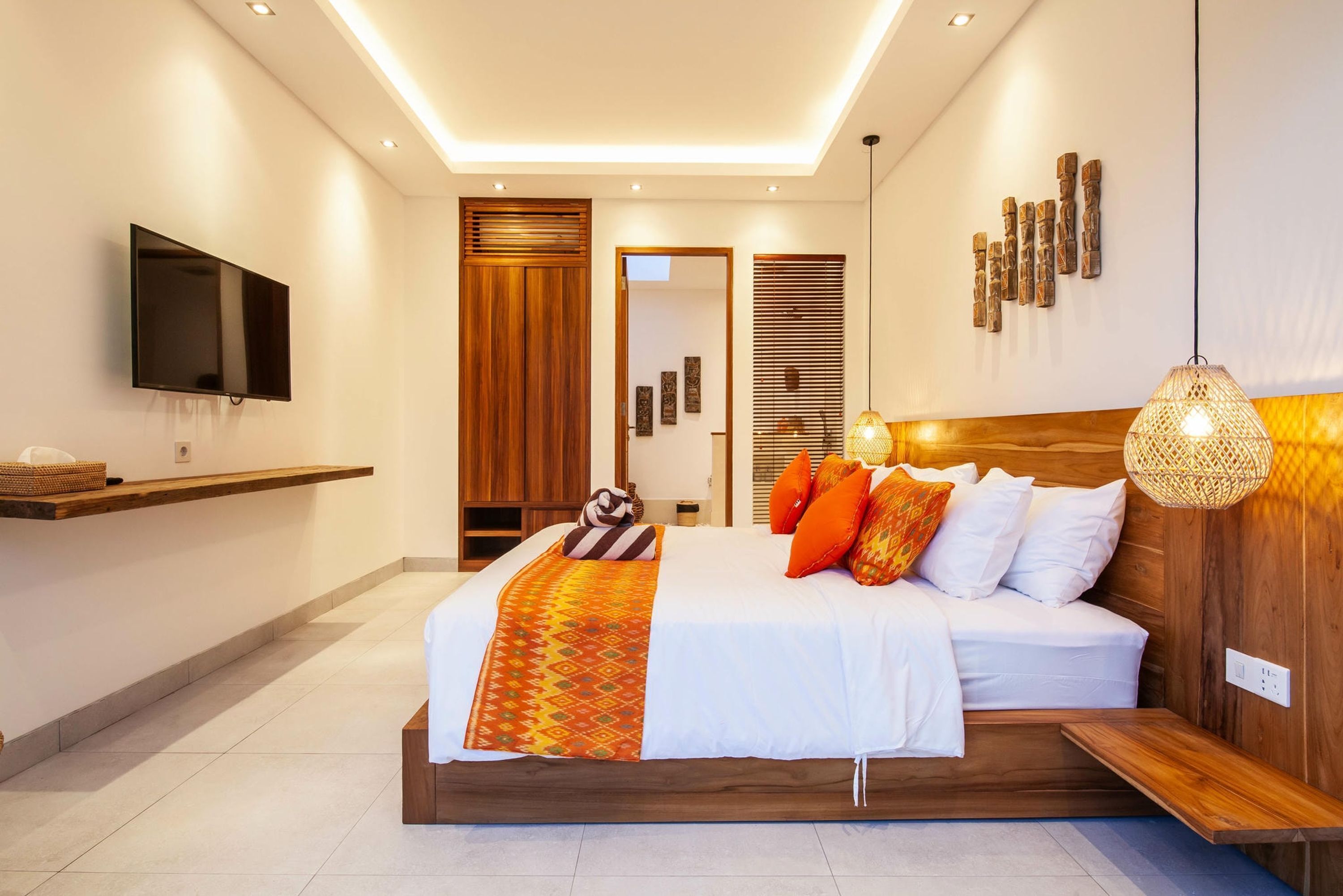 A modern bedroom with a large bed, a flat-screen TV, and a wooden headboard.