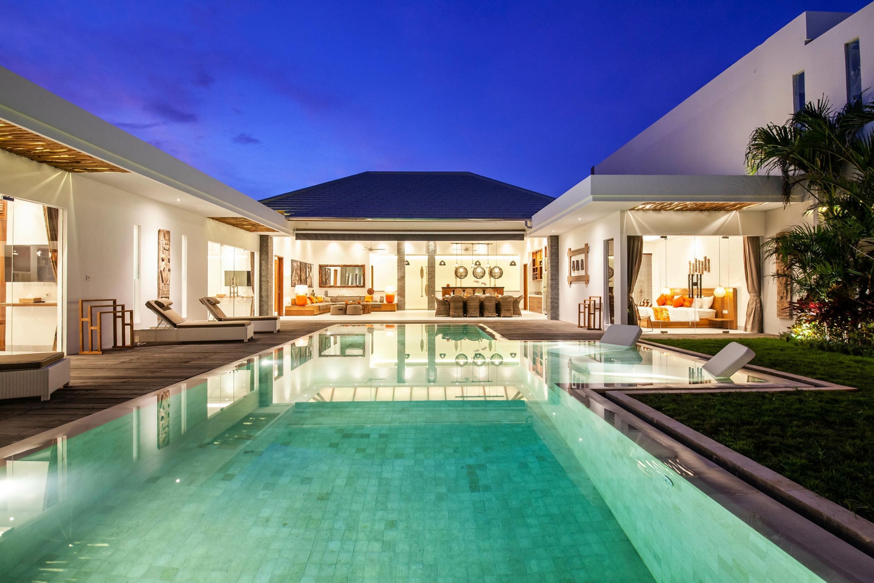 A modern house with a central pool, two lounge areas, and a dining space.