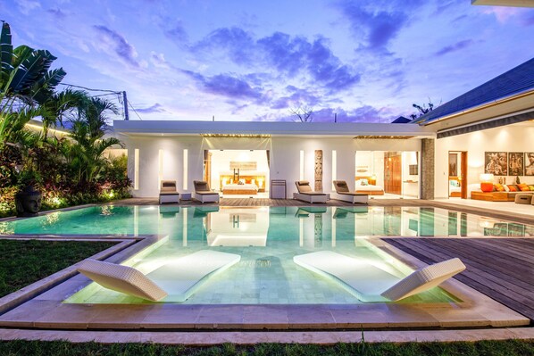 A modern outdoor pool area with lounge chairs and a spa-like setting.