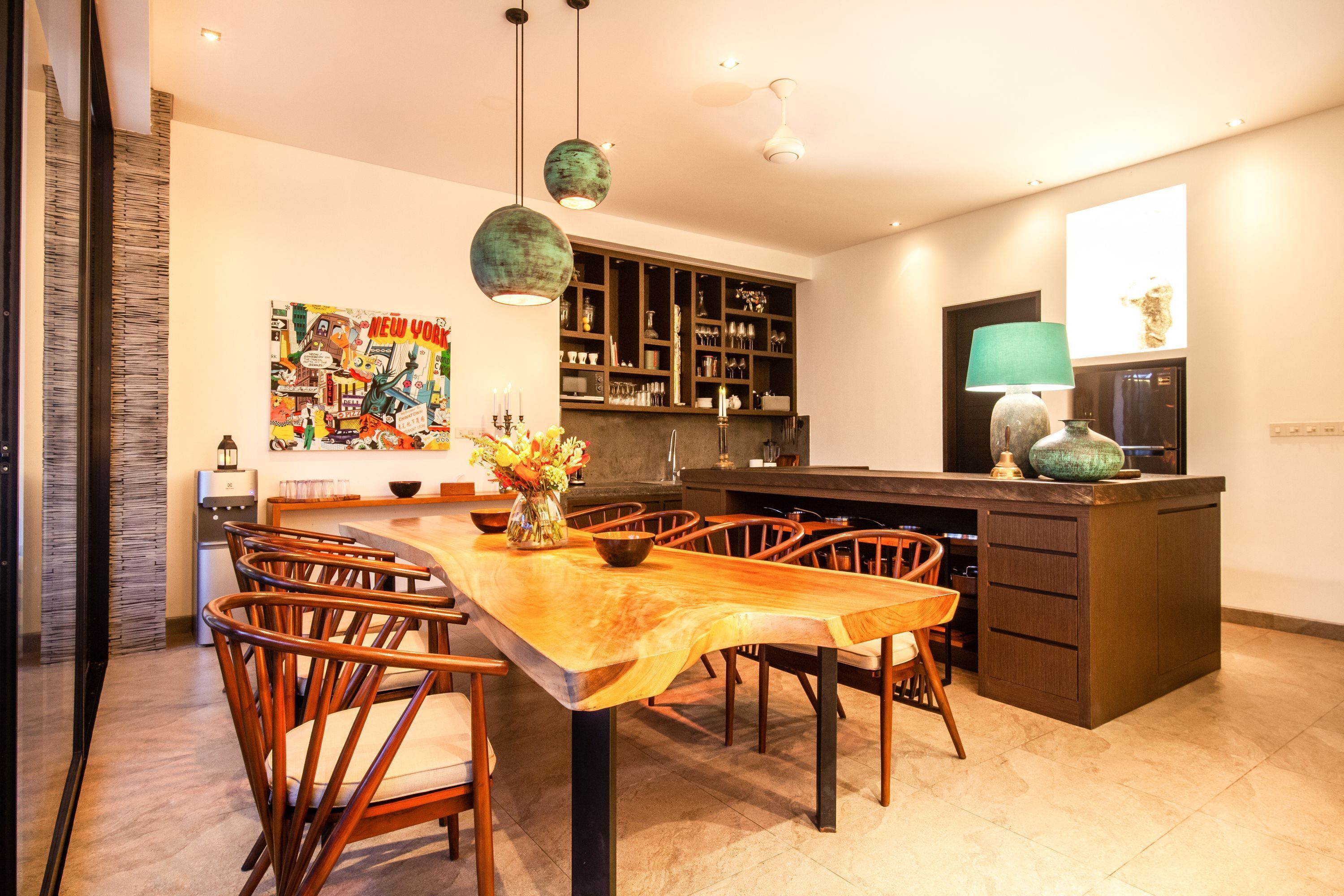 Una cocina moderna con una isla de madera, luces colgantes y un mural grande.