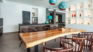 A spacious kitchen with a large wooden table and chairs, a built-in island, and modern pendant lighting. - Mette 3br Villa in Dalung (Canggu)