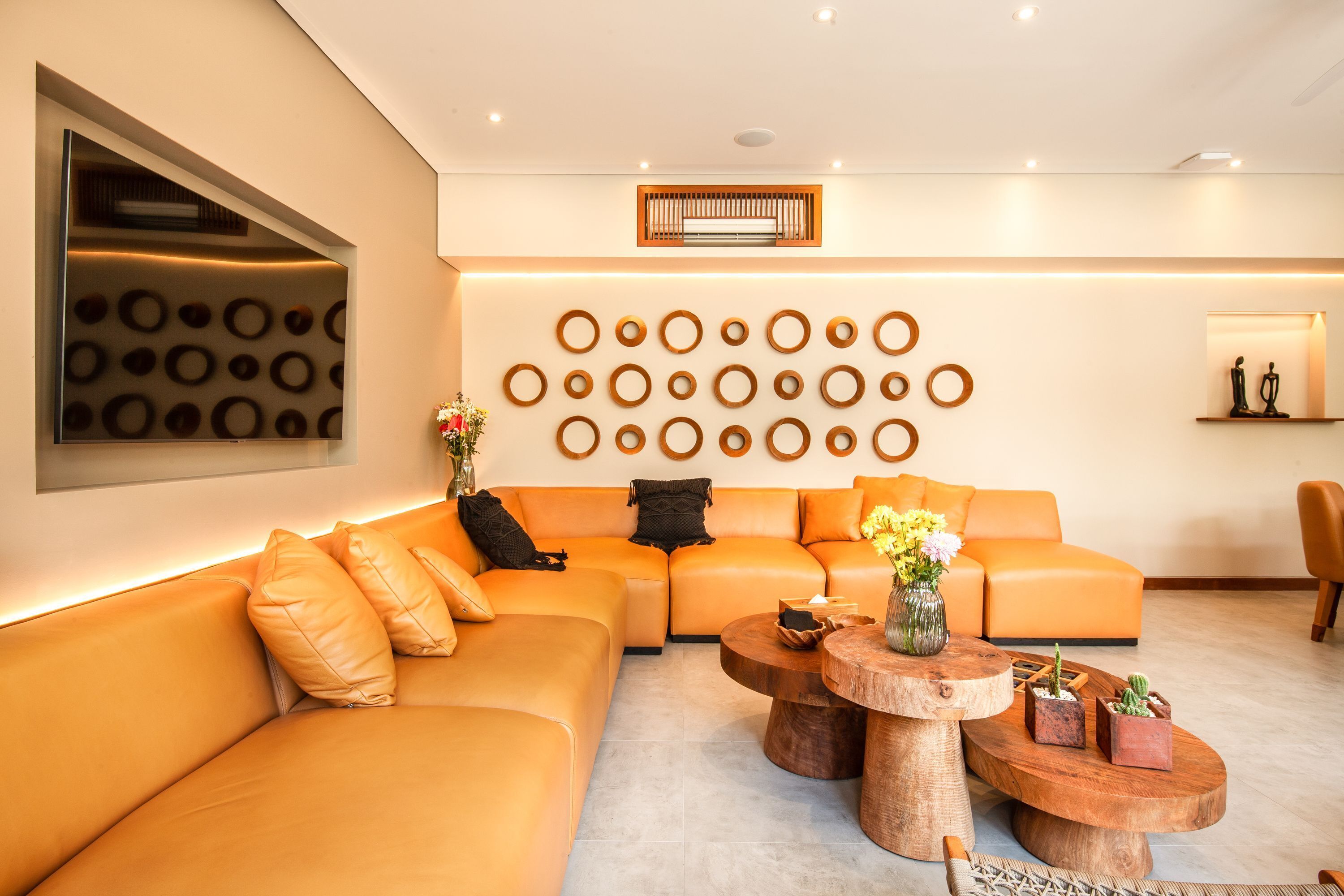 A modern living room with a sectional sofa, wooden coffee tables, and a wall with circular patterns.