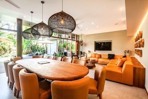 A modern interior with a wooden dining table surrounded by chairs, a sofa, and a coffee table. - Villa Na in Canggu With 6 Bedrooms and 6 5 Bathrooms (Tibubeneng)