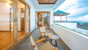 A balcony with wicker chairs and a small table, wooden doors, and a view of the ocean. - Breeze Opulent 6 BR in With Ocean View 5 Mins to Savaya (Pecatu)