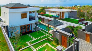 A modern two-story house with a swimming pool, a balcony, and a view of the ocean. - Breeze Opulent 6 BR in With Ocean View 5 Mins to Savaya (Pecatu)